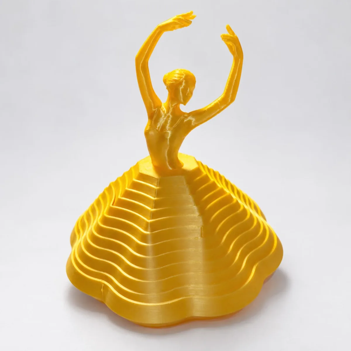Escultura dourada de uma bailarina com a saia formada por camadas onduladas